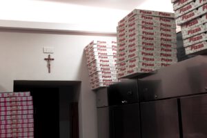 Un crucifix dans une pizzeria avec des boite de pizza