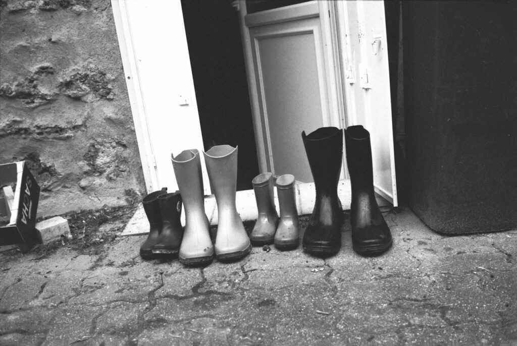 Quatre paires de bottes de taille différentes le long d'un mur avec une porte entre-ouverte