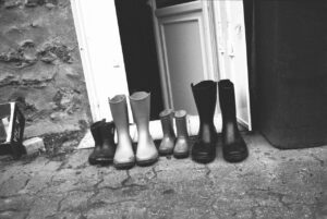 Quatre paires de bottes de taille différentes le long d'un mur avec une porte entre-ouverte